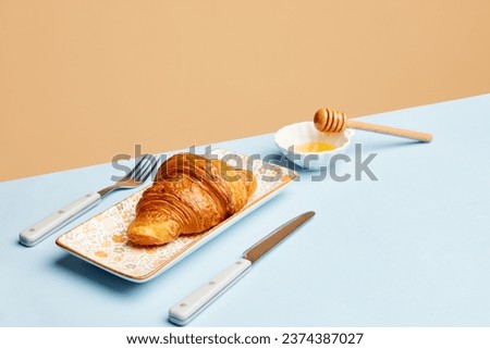 Continental breakfast. Crispy croissant with honey over beige background. Sweet food. Concept of food, bakery, breakfast ideas, taste, freshness. Poser. Copy space for ad