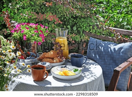 Continental breakfast on the garden table. Country lifestyle or weekend morning concept. Peaceful rural scenery.