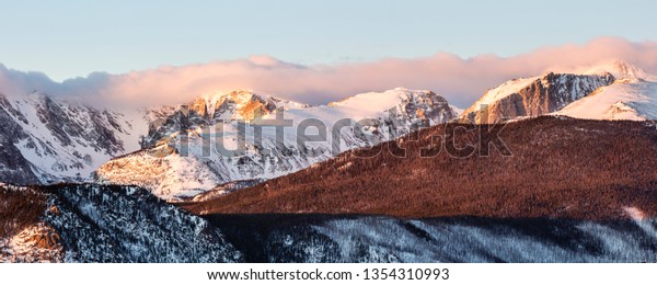 The Continental Divide crowned with a line of\
clouds in the early morning sun in Rocky Mountain National Park,\
Colorado.