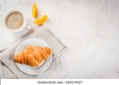 Continental Traditional Breakfast. Croissant, A Cup Of Coffee And An Orange. On A White Stone Concrete Table. Copy Space Top View