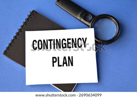 CONTINGENCY PLAN - words on a white sheet on a black notebook with a magnifying glass