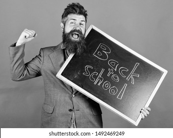 Continue Education Private School. Teacher Or Educator Welcomes Students While Holds Chalkboard With Inscription Back To School. Teacher Begin First Lesson After Holidays. School And Studying Concept.