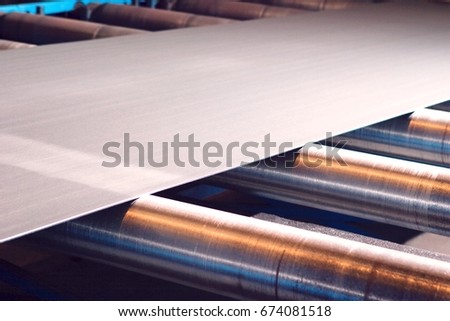 Continuous sheet of metallic material being fed through machine