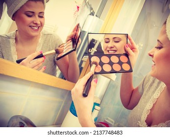 Contouring face kit, visage and make up concept. Woman in bathroom applying contour bronzer on brush