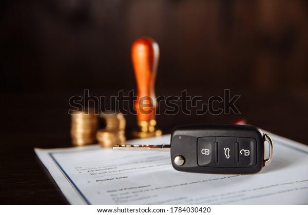 Contract form for car loan, stamp, pen and car key\
on wooden table
