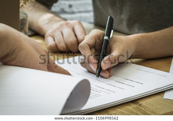 Contract\
signature for business and financial contract.  Sign on the dotted\
line.  Male caucasian pen signs a\
paper.