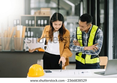 Contractor and architect looking at plan, tablet, laptop and talking about working on big project. Building in construction office process interior.