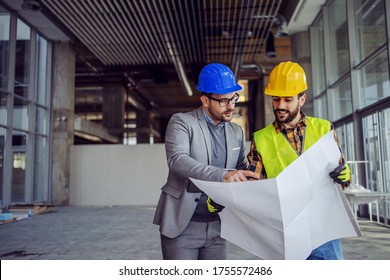 Contractor and architect looking at plan and talking about working on big project. Building in construction process interior. - Shutterstock ID 1755572486