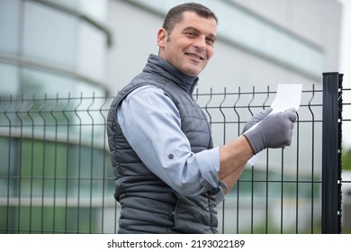 A Contractor With Brush That Painting Metal Fence