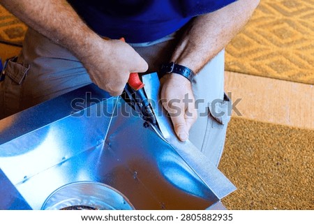 Contractor cuts metal precisely with tin snips in home office project.