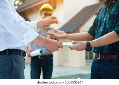 The contractor delivers the keys to the house and receives the payment after completing the construction project. - Shutterstock ID 1886535967