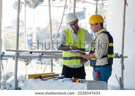 Contractor and engineer architect working together planning using tablet technology construction industry, building house innovation and teamwork discussing, two male caucasian collaborating.