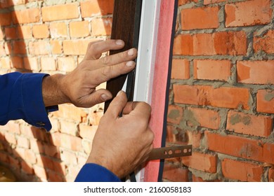 Contractor Glue Waterproofing And Insulation Tape On New House Window Installation. Close Up On Window Installation.