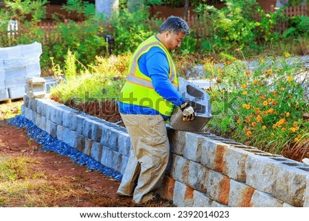 Contractor is installing concrete block walls as part construction of retaining walls