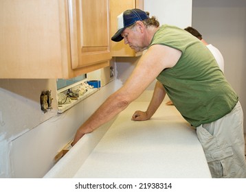 Contractor Installing Laminate Counter Top During A Kitchen Remodel.