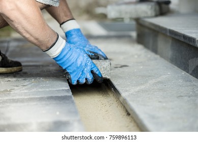 Contractor laying new paving bricks or stones, close up view of his gloved hands. - Shutterstock ID 759896113