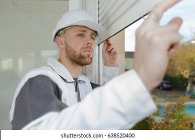 Contractor Looking At Window Roller Shutter