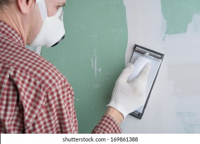 Contractor Sanding The Drywall Mud Using Sand Trowel