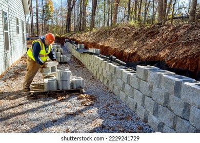 Contractor was seen installing concrete block wall that is being built on part new retaining wall construction project - Shutterstock ID 2229241729