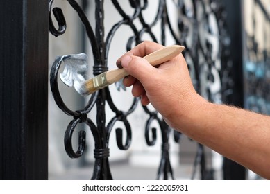 Contractor's Hand With Brush That Painting Metal Fence. 