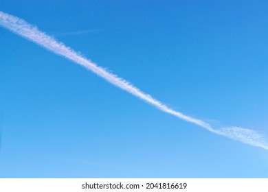 Contrail after an airplane, or a spill of chemicals in the air against a blue sky.