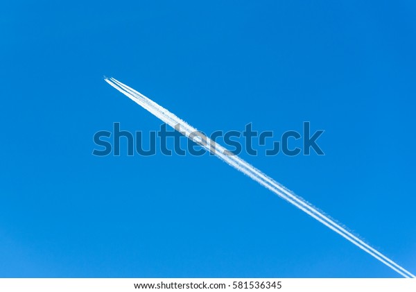 Contrails or vapor trails after a large commercial\
jet plane high in blue\
sky.