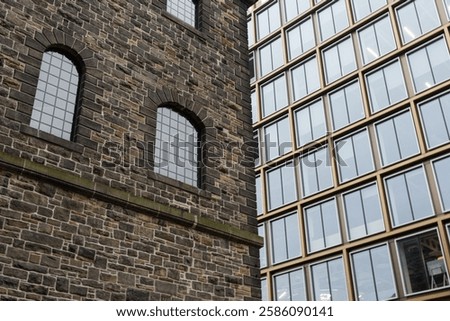 Contrast between historic brick wall and modern glasss building