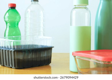 Contrast between regular disposable packaging and its green alternative: metal thermos, glass bottle, container and plastic waste. Resource awareness, new consumer culture, modern material choices.