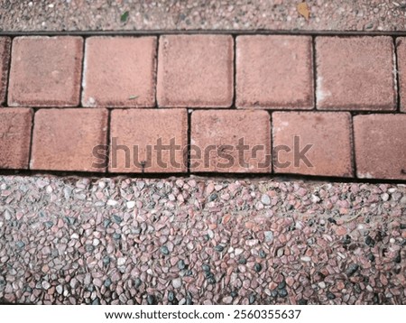 contrast between two different surfaces: red brick tiles with a smooth texture and a terrazzo-like concrete finish with embedded pebbles