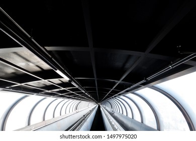 Contrasting Black And White Architectural Image Of A Moving Walking With Tunnel Perspective Into Distance.Dark Roof Strong Highlights To Side Windows And A Black Walkway - Image