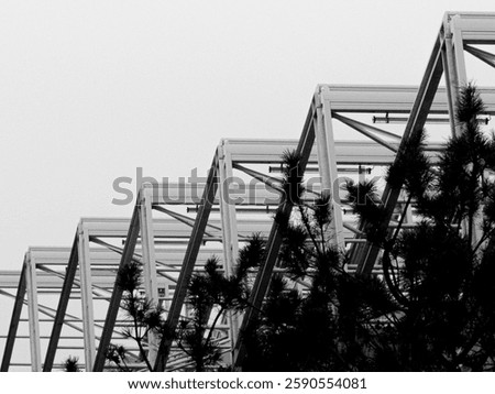 Contrasting composition of a triangular metal structure in contradiction with the greenery (trees, shrubs). Photo taken from below at an upward angle, from a low angle. Ecology and industrial concept.