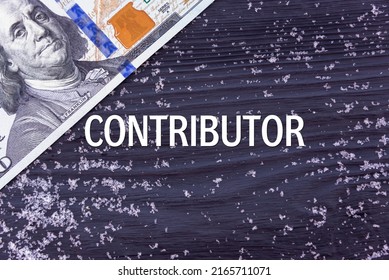 CONTRIBUTOR - word (text) on a dark wooden background, money, dollars and snow. Business concept (copy space).