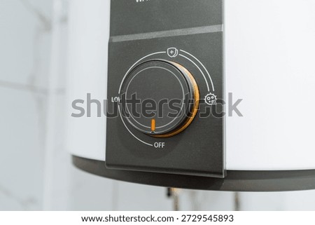 Control Dial Set To Medium On Water Heater With Clear Markings And Energy Icon, Closeup Of Knob Shows Calibration, Eco Setting, And Modern Appliance Interface For Energy Efficient Smart Home Messaging