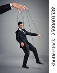 Control, hand and puppet with business man on strings in studio for corporate propaganda or management. Art, abstract or creative with master puppeteer and employee on gray background for authority