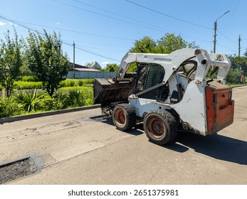 A re -control loader drops asphalt on the side of the road.