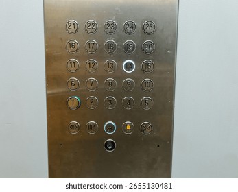 The control panel for the elevator, made of stainless steel, features buttons clearly labeled with numbers ranging from 1 through 12, facilitating easy navigation to different floors