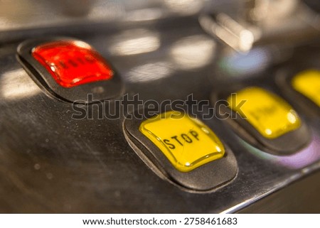 The control panel of a gaming machine features a row of illuminated square buttons in red and yellow. These 