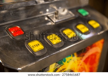 The control panel of a gaming machine features a row of illuminated square buttons in red and yellow. These 