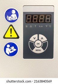 A control panel of a modern laboratory water bath with safety signs. Stickers with pictograms indicates that a user should refer to instruction manual and remain cautious.