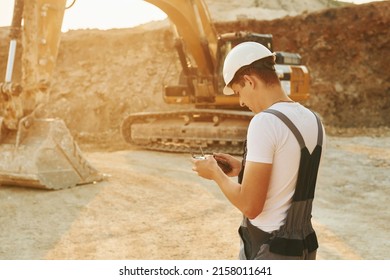 Control of the project. Worker in professional uniform is on the borrow pit at daytime.