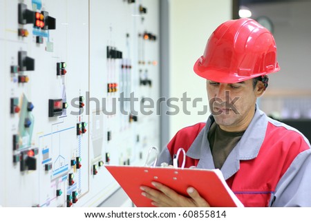 Control Room Engineer. Power plant control panel.
Engineer standing in front of the control panel in the control room and writes the results of measurements.