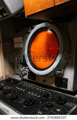 Control station with periscope screen inside historic submarine. Vintage naval navigation and control console with German labels such as “Bild verstellen” meaning “adjust image”. Military maritime technology and engineering interior detail.