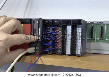 Control system testing. An electrical engineer checks the connection of the PLC automaton.  Production automation. Automatic control system.