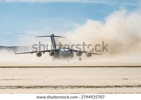  controller assigned to the 66th Weapons Squadron, U.S. Air Force Weapons School, marshals a C-17 Globemaster III aircraft assigned to the 57th Weapons Squadron, USAFWS, after landing on a dirt runway at Delamar Dry Lake near Alamo, Nevada, May 28, 2026. The 66th and 57th WPS participated in a Weapons School Integration mission, challenging students to develop tactically relevant plans integrating multiple mission partners. 