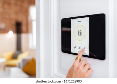Controlling home alarm system with a digital touch screen panel installed on the wall. Concept of wireless secure control and smart home