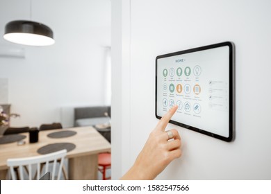 Controlling Home With A Digital Touch Screen Panel Installed On The Wall. Close-up On A Screen With Mobile Application For Managing Smart Devices