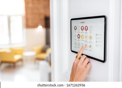 Controlling Home With A Digital Touch Screen Panel Installed On The Wall In The Living Room. Concept Of A Smart Home And Mobile Application For Managing Smart Devices At Home