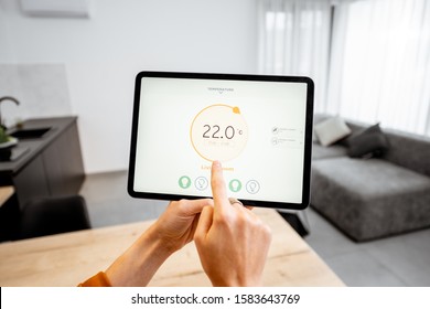 Controlling home heating temperature with a digital tablet. Concept of a smart home and mobile application for managing smart devices at home - Shutterstock ID 1583643769
