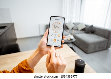 Controlling home heating temperature with a smart home, close-up on phone. Concept of a smart home and mobile application for managing smart devices at home - Shutterstock ID 1584383977