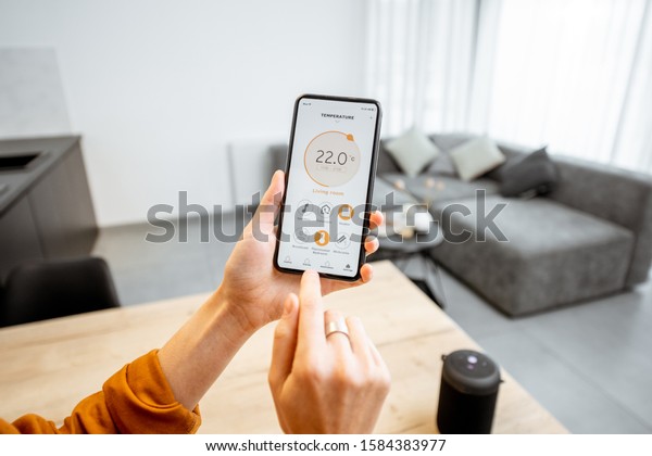 Controlling home heating temperature with\
a smart home, close-up on phone. Concept of a smart home and mobile\
application for managing smart devices at\
home